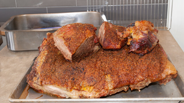 Pieza grande de roast beef cocinada en charola de acerco con trozos de carne encima