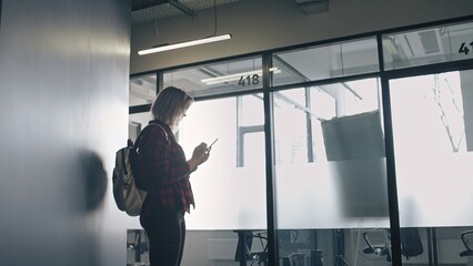 Casual young woman using smartphone in coworking space, modern technology