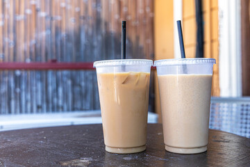 An iced frappe coffee and a regular iced coffe both sitting on a small table outdoors at a locally owned coffee shop in Hawaii