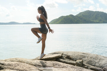 Fototapeta na wymiar A Beautiful fit woman in sportswear exercising on seaside mountain peak, Health and Travel concept.