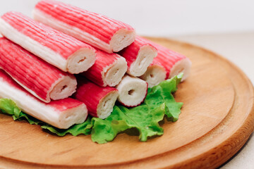 Crab sticks surimi rolls stacked in a pyramid on a wooden board.
