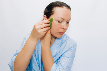 The girl makes a massage with a jade massager close-up, problem skin.