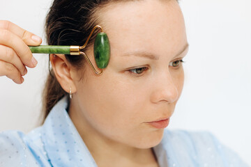 The girl makes a massage with a jade massager close-up, problem skin.