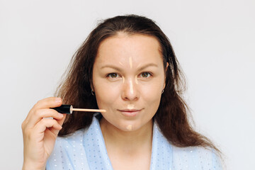 The girl applies concealer light corrector on the face, in the corners of the eyes.