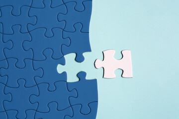 Dark blue jigsaw puzzle with some missing pieces on blue background. Flat lay.