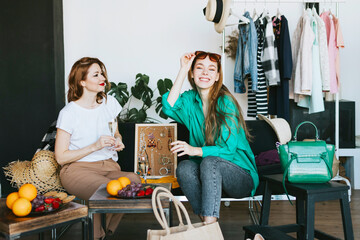 two young woman female caucasian students at swap party try on clothes, bags, shoes and...