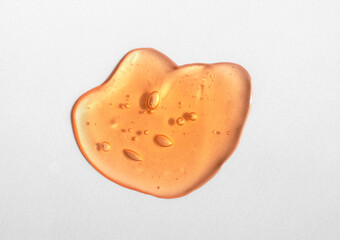 Orange cosmetics gel, serum or peeling drop on white background. Colorful warm yellow slime with...