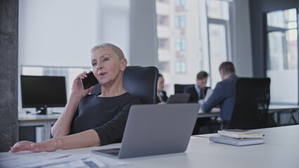 Relaxed business woman having conversation on phone in office, productive day