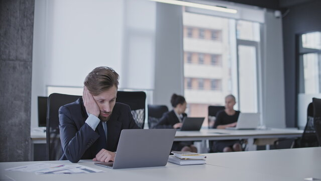 Bored Office Worker Looking At Laptop Screen, Having No Desire To Work, Procrastination