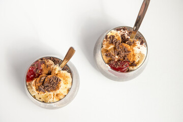 Chia seeds from the Salvia hispanica plant. Glass cup with hydrated seeds, natural yogurt, banana, strawberry jam, cinnamon powder and chocolate shavings. Image seen from above on white background.