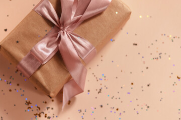 Valentines Day, Birthday or New Year present in kraft paper with pink ribbon on soft beige background with glitter and heart-shaped bokeh. Flat lay. Happy holidays celebration and giving love concept