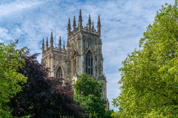 Fototapeta na wymiar close-up view of the bell towers of the York Minster surrounded by colorful summer trees under a blue sky