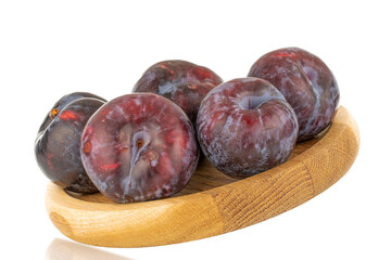Several ripe black plums on a wooden tray, close-up, isolated on a white background.