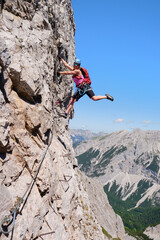 Obraz premium Active woman on vertical via ferrata at Nordkette, Innsbruck, Austria. Rock details, adventure, activity, tourism, klettersteig.