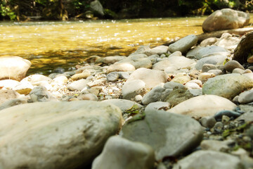 Boulders and pebbles on the shore of mountains river.