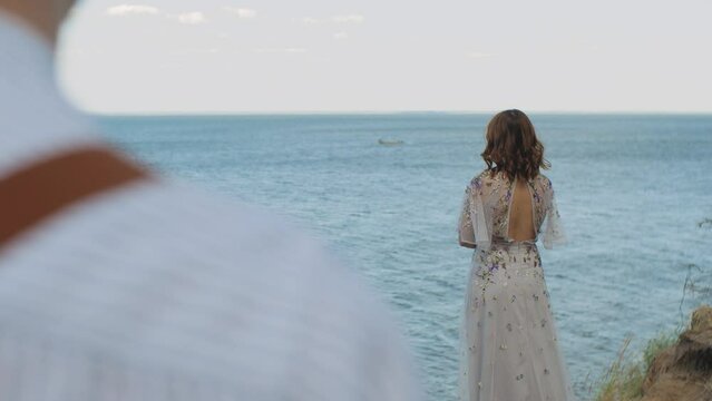 A woman admires the sea where white clouds merge with the water on the horizon. slow motion. Rear view
