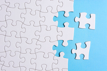 White jigsaw puzzle with some missing pieces on blue background. Copy space.