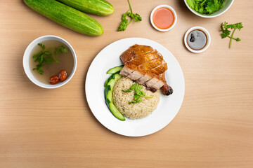 Roasted Chicken and Roast Pork Rice with raw cucumber, Coriander, salad, sauce and soup served in a dish isolated on wooden background top view