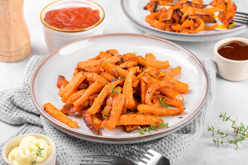 Sweet potato fries on a plate with mayo and ketchup, bbq sauce homemade roasted in the oven