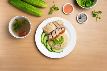 Steamed Chicken and Roast Pork Rice with raw cucumber, Coriander, salad, sauce and soup served in a dish isolated on wooden background top view