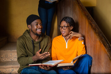 Smiling African male and female college student friends discussing about their books