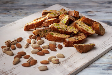 Close up of sweet italian cantuccini cookies with pistachios and almonds. Pistachios and almonds on a board