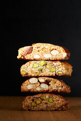 Stack of sweet fresh italian cookies cantuccini with pistachios and almonds on ructic wooden dark table background
