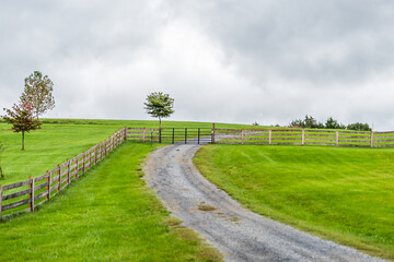 Farm rural countryside with fence in Rockbridge County in Buena Vista, Virginia during fall season with cloudy day and dirt road driveway on hill - obrazy, fototapety, plakaty