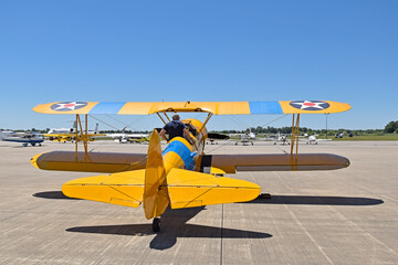 The pilot climbs into the cockpit of a biplane to take off at an airshow.