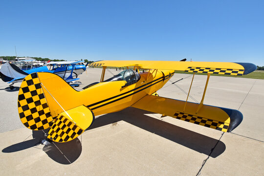 A Small Stunt Biplane Sits On The Tarmac At An Airshow Under A Brilliant Sky.