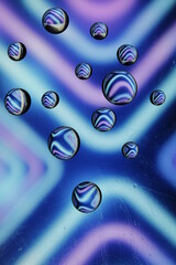Burbujas de agua en la superficie copian el dibujo por reflexiòn formando lìneas y estrellas de colores, muestra un original diseño abstracto con fondo colorido en bokeh