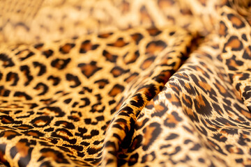 Satin fabric close up background and texture with place for text. Leopard print, silk orange.