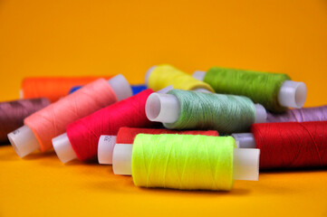 Reels with multicolored threads on a yellow background. Blur.
