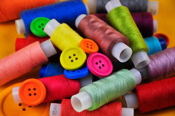 Set of multicolored buttons and Spools threads on a yellow background. Blurring.