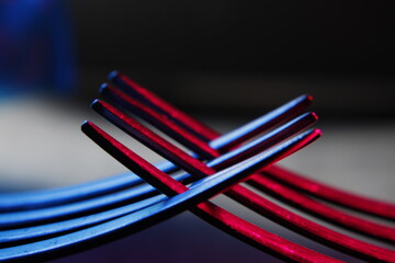 Tenedores de acero entrelazados por sus dientes es usado como instrumento culinario, con luz azul y rojo, forman un bello y original diseño abstracto con fondo negro