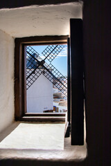 View through an open wooden window at a windmill in Campo de Criptana, Spain.