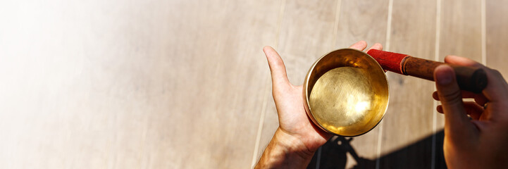 Man hands using singing bowl in sound healing therapy outdoors, closeup banner