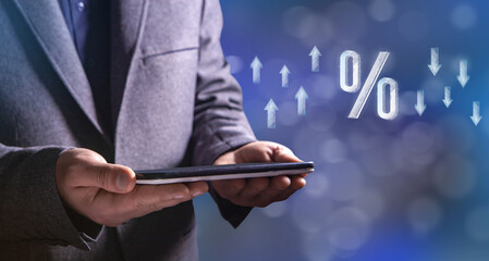 Icon of percentage and up and down arrows from web. Man holding a tablet in his hand