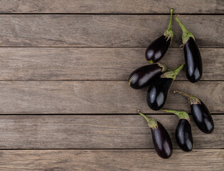 Tiny baby eggplants over wooden table with copy space