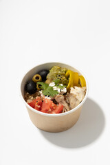 meat soup with vegetables in a paper cup on a white background