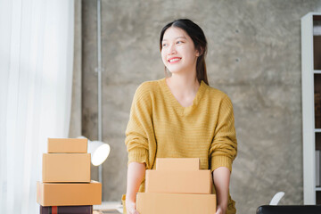 Asian SME business women use laptop computer checking customer order online shipping boxes at home....