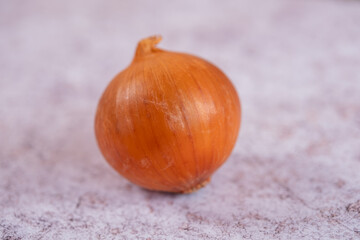 A whole onion on a white stone surface background.