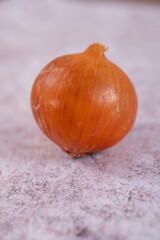 A whole onion on a white stone surface background.