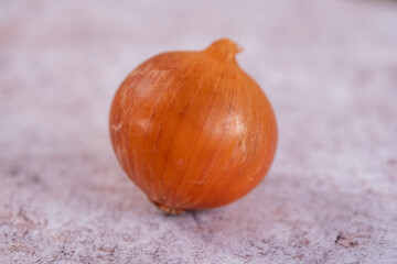 A whole onion on a white stone surface background.