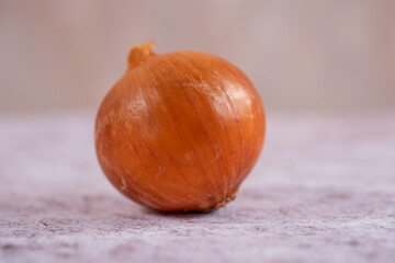 A whole onion on a white stone surface background.