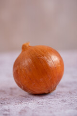 A whole onion on a white stone surface background.