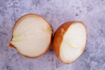 A halved onion on a marble surface background.