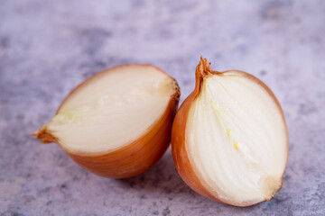 A halved onion on a marble surface background.