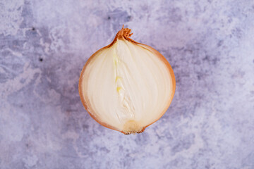 A halved onion on a marble surface background.