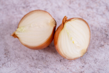 A halved onion on a white stone surface background.